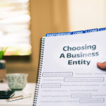 Book titled "Choosing a Business Entity" with tabs labeled LLC, S-Corp, Corp, and Partenrship representing different business structure options.